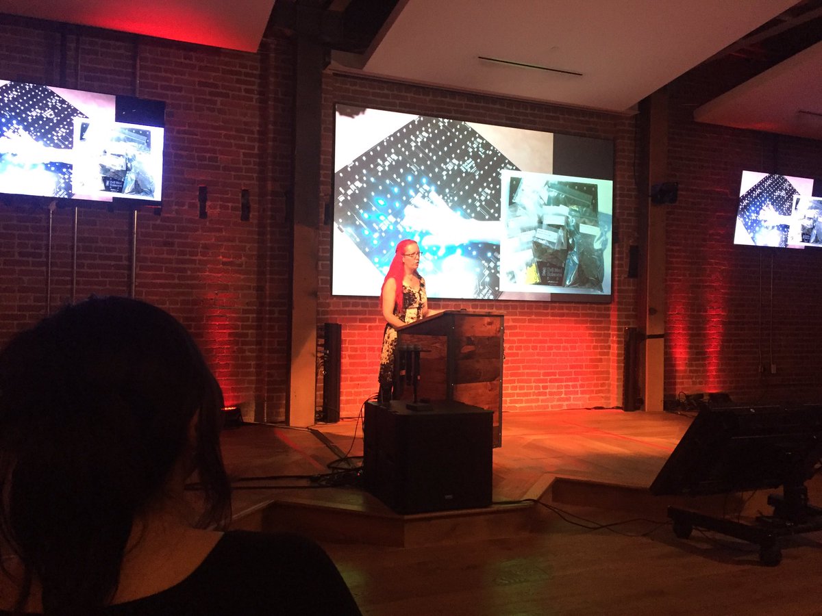 Lenore on stage with slide of electronic kits in background