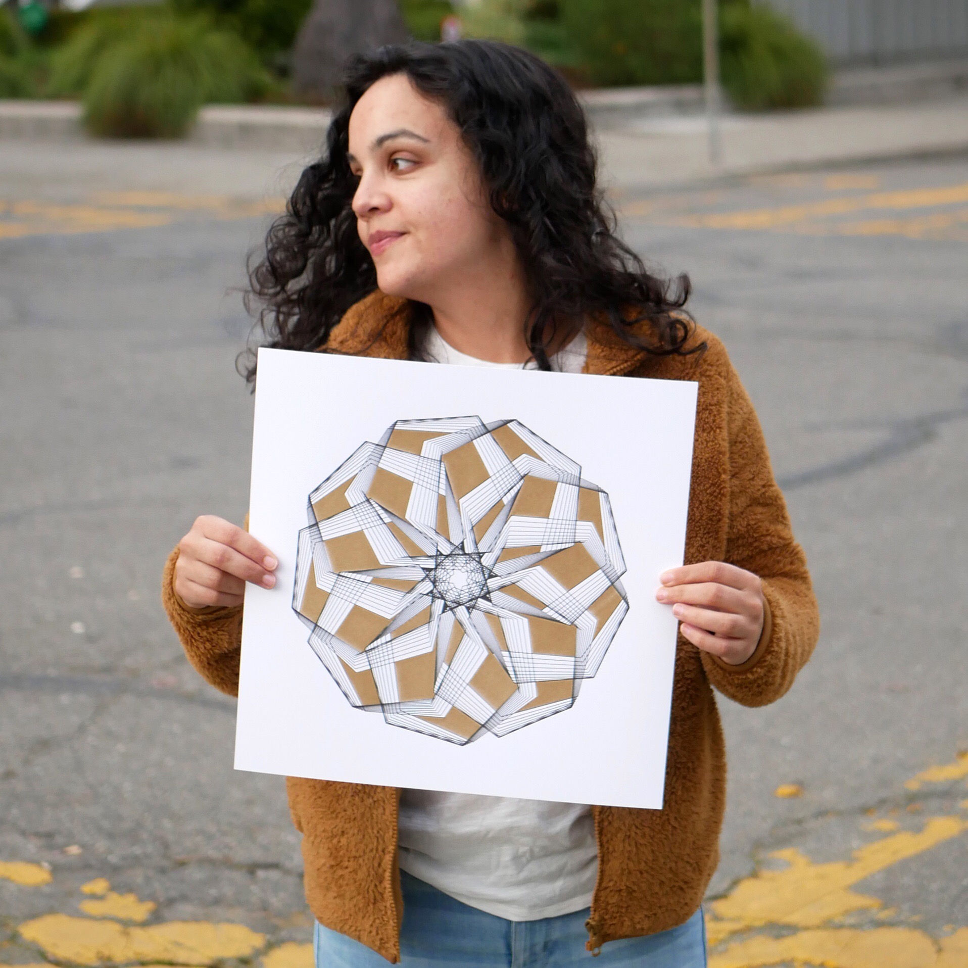 Michelle Chandra holding a gold and black plot on white paper in front of her